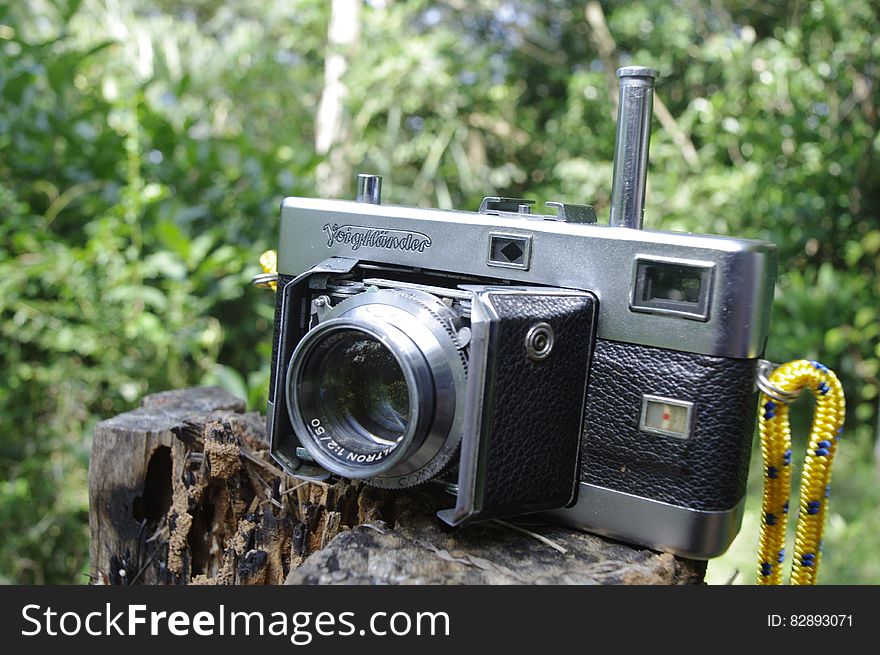 A vintage VoigtlÃ¤nder film camera on a tree stump. A vintage VoigtlÃ¤nder film camera on a tree stump.