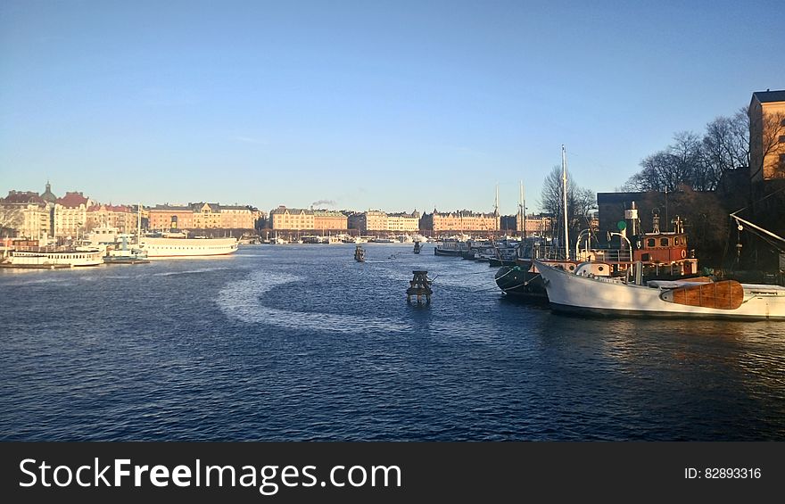 Panoramic view of a wide river flowing through a city with boats in the foreground.