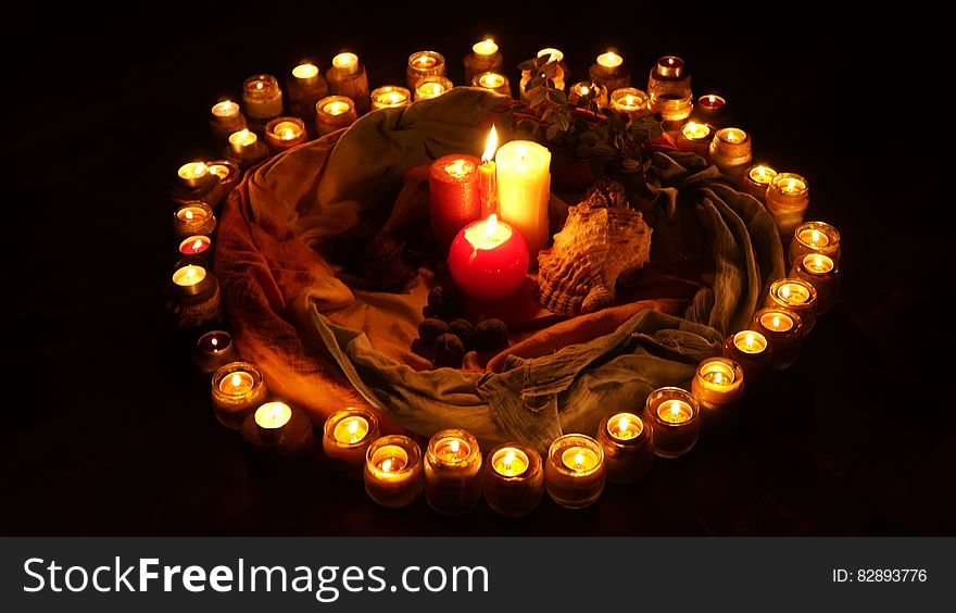 Circle of lit candles around candlesticks and shell with black background. Circle of lit candles around candlesticks and shell with black background.