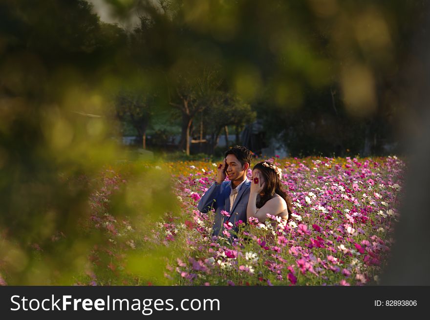An Asian couple standing on a field full of blossoming flowers. An Asian couple standing on a field full of blossoming flowers
