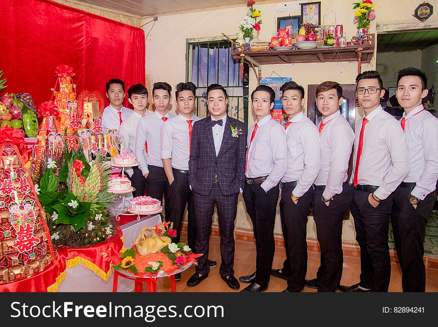 A group of Asian men standing in line next to a table. A group of Asian men standing in line next to a table.