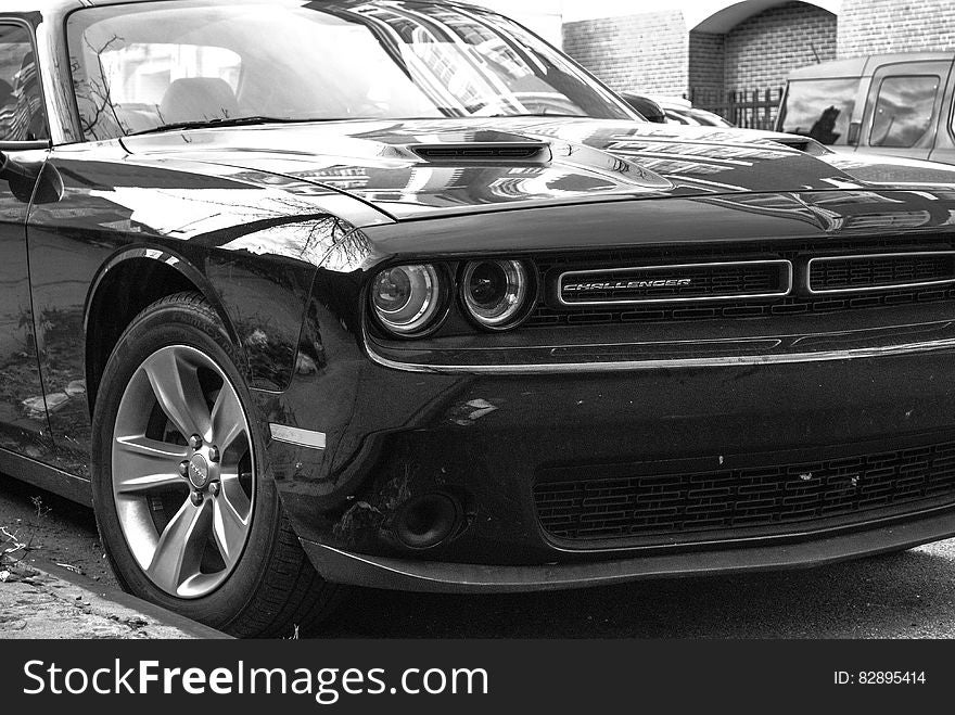 Closeup of gleaming black sports saloon parked on roadside with double headlights, air snoop on bonnet and alloy wheels. Closeup of gleaming black sports saloon parked on roadside with double headlights, air snoop on bonnet and alloy wheels.