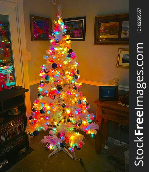 A colorful Christmas tree standing in the living room of a home.