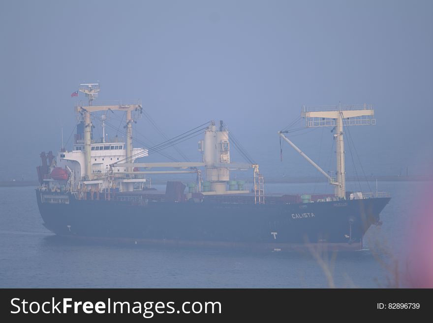 Large ship, maybe oil tanker, with dark hull and white superstructure sailing on a calm sea, gray sky. Large ship, maybe oil tanker, with dark hull and white superstructure sailing on a calm sea, gray sky.