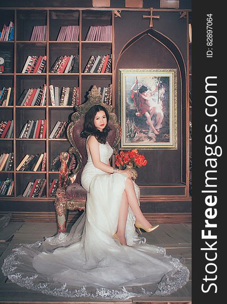 Portrait of Asian bride in white gown sitting in chair inside library. Portrait of Asian bride in white gown sitting in chair inside library.