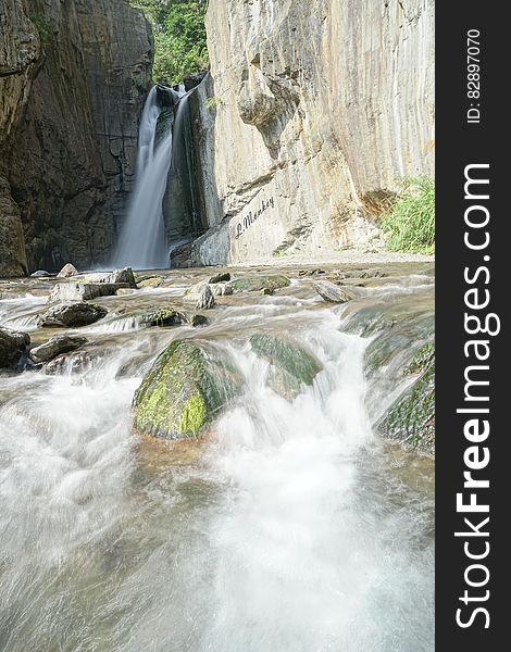 Waterfalls into rocky pool on sunny day. Waterfalls into rocky pool on sunny day.