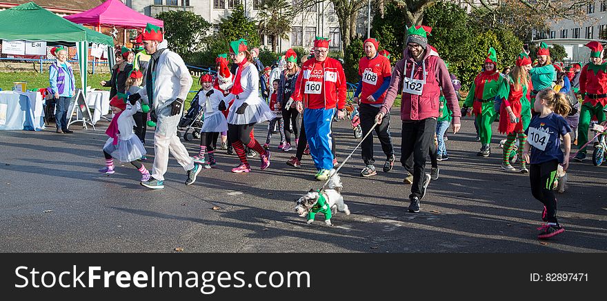 Parade of people dressed as Christmas elves walking on sunny city street. Parade of people dressed as Christmas elves walking on sunny city street.