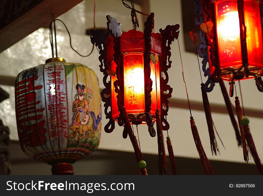A close up of lit Chinese lanterns hanging from a beam.