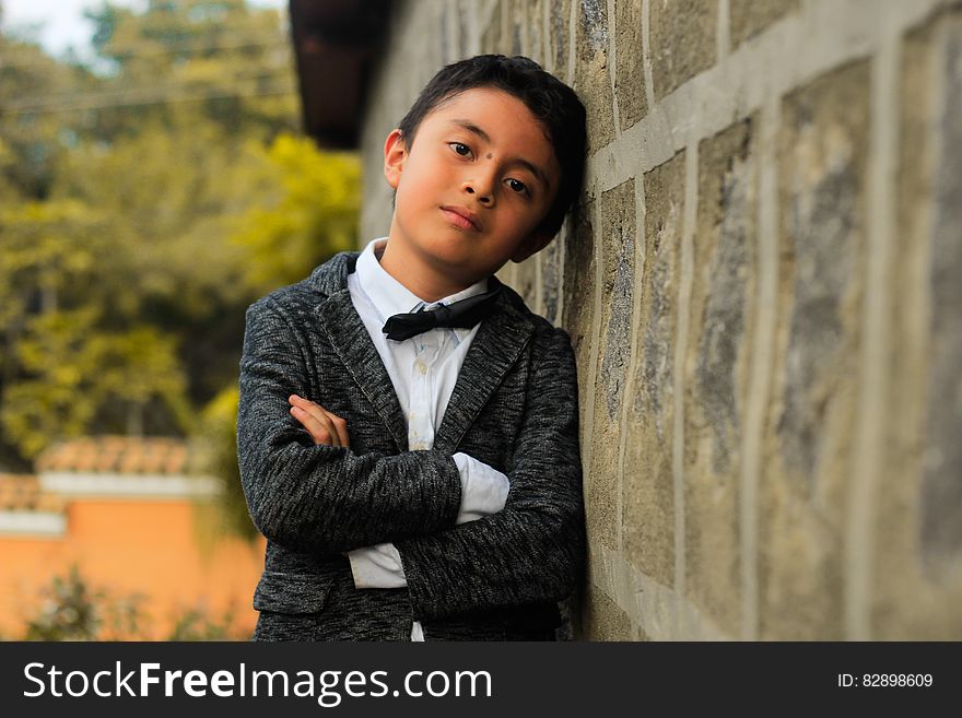 An elegantly dressed boy leaning against a wall. An elegantly dressed boy leaning against a wall.