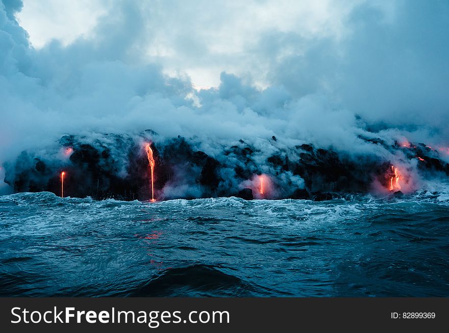 Lava streams flowing into water with steam and waves. Lava streams flowing into water with steam and waves.