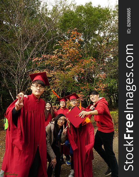 Graduating boys and girls in red mortar board caps and gowns in outdoor group portrait. Graduating boys and girls in red mortar board caps and gowns in outdoor group portrait.