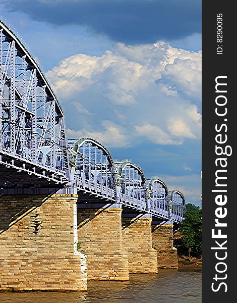 Multiple section bridge spanning over a river with blue sky above
