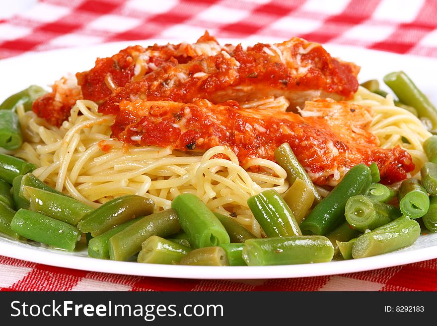 Chicken parmesan surrounded by green beans with spaghetti