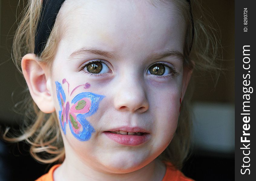 Little girl with beautiful brown eyes and a butterfly painted on her cheek. Little girl with beautiful brown eyes and a butterfly painted on her cheek.