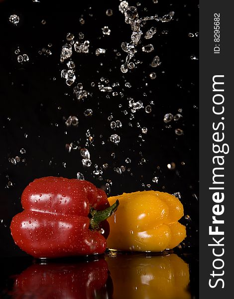 Fresh peppers and water splashes, isolated on black background