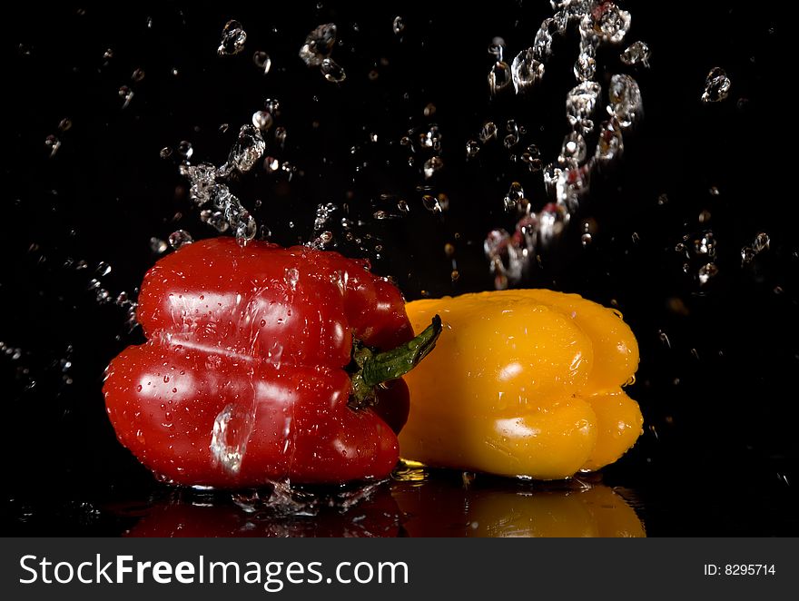 Bright peppers and water splashes, isolated on black background