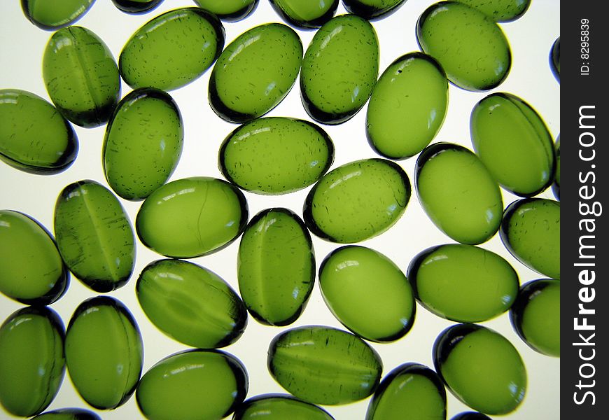 Scattered oval green pills on a white background.