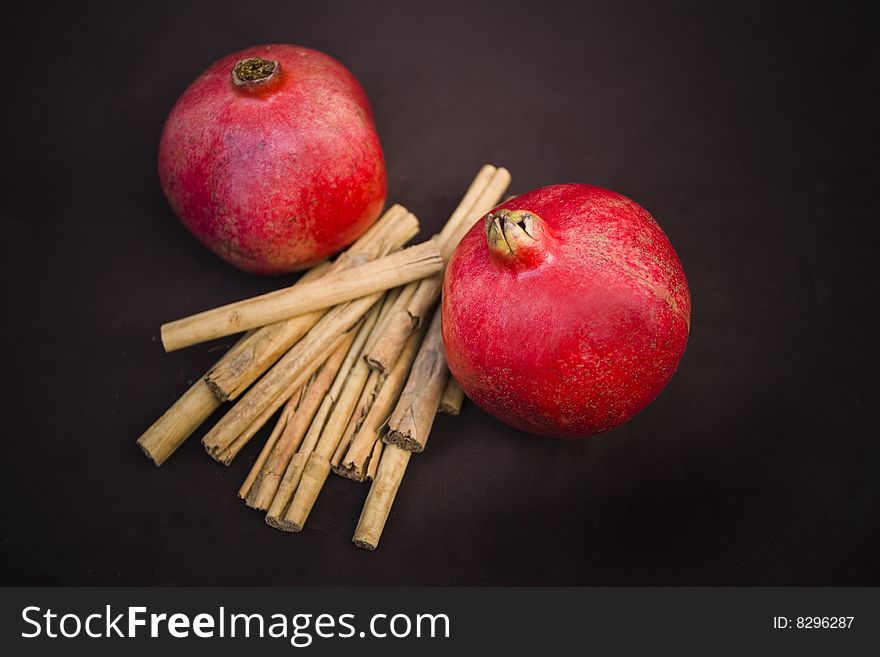 Studio shot of pomegranates and cinnamon on brown background