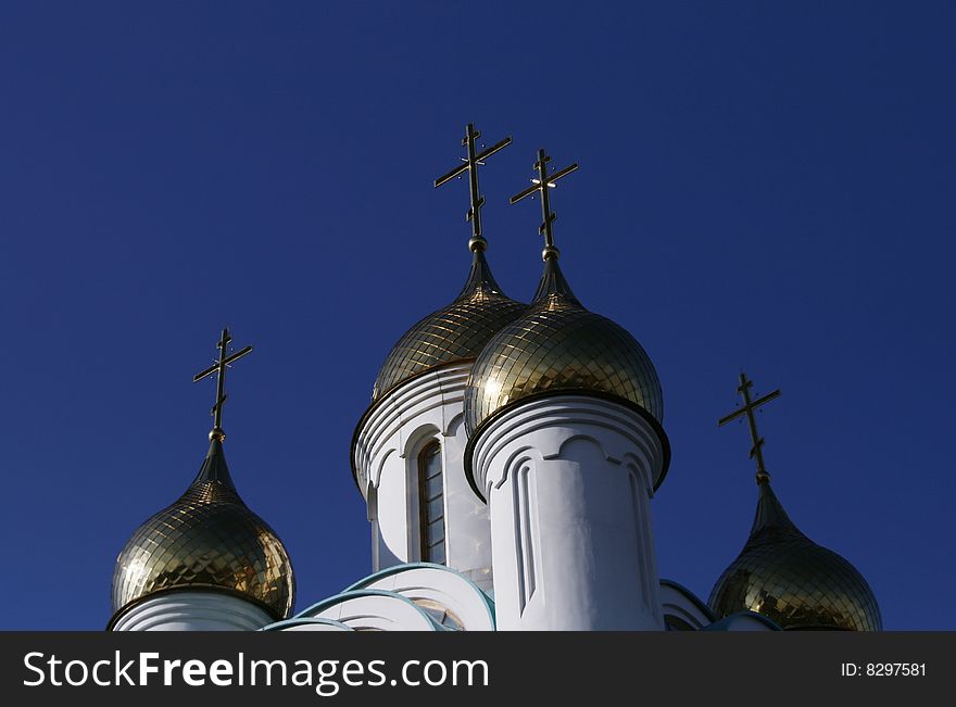 Gold cupola with the crosses over big blue sky