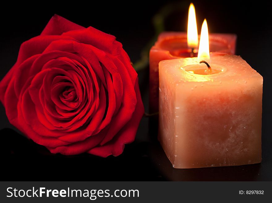 Red rose and candles over black background