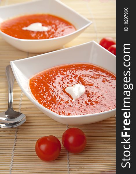 Tomato soup in white plates over bamboo mat. Tomato soup in white plates over bamboo mat