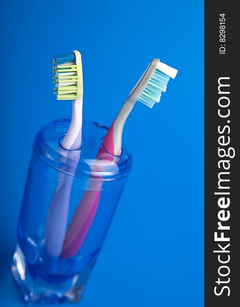 Two colorful toothbrushes over blue