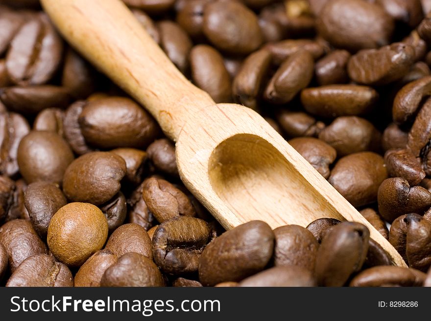 Small wooden scoop among coffee beans. Small wooden scoop among coffee beans