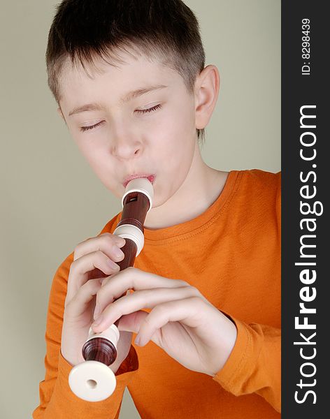 Boy in a bright T-shirt playing the flute. Boy in a bright T-shirt playing the flute