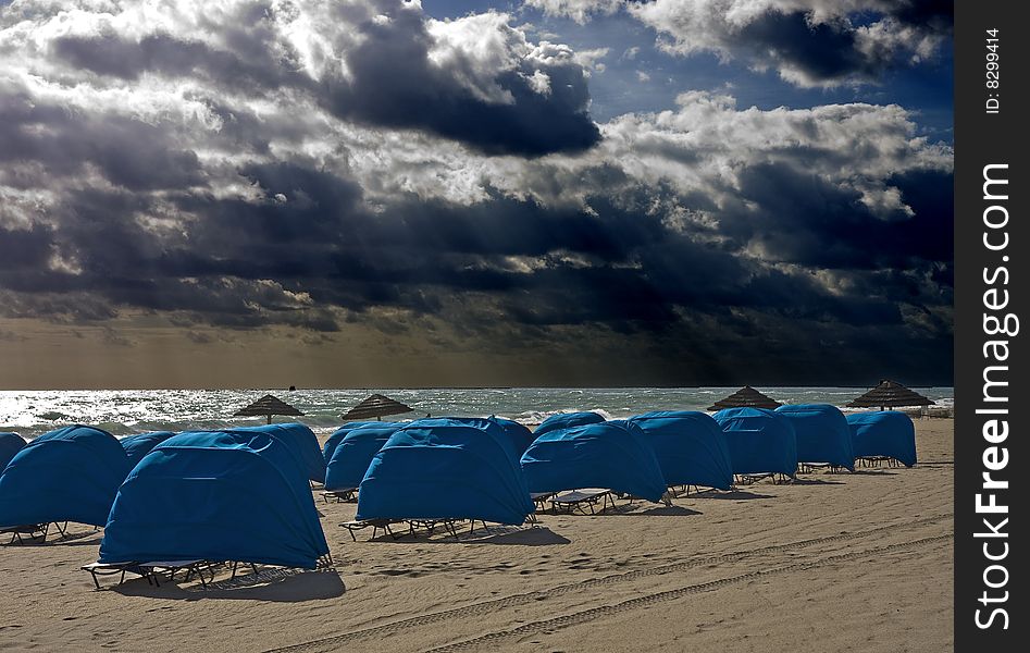 Blue Beach Shelters and Umbrellas on a beach on a cloudy day. Blue Beach Shelters and Umbrellas on a beach on a cloudy day