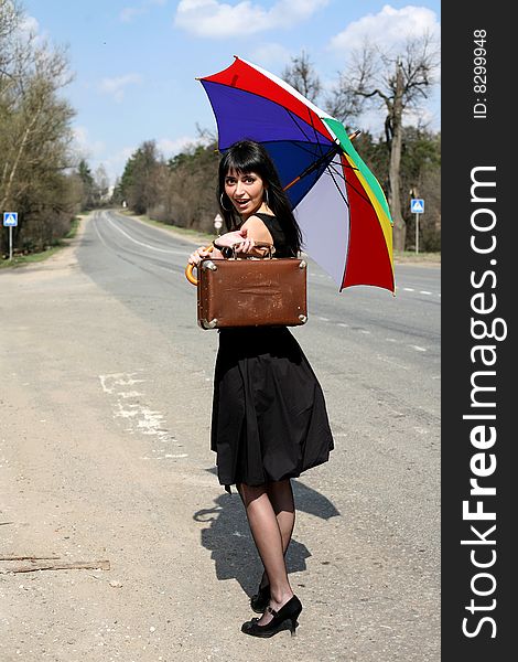 Girl with vintage suitcase and umbrella outdoors