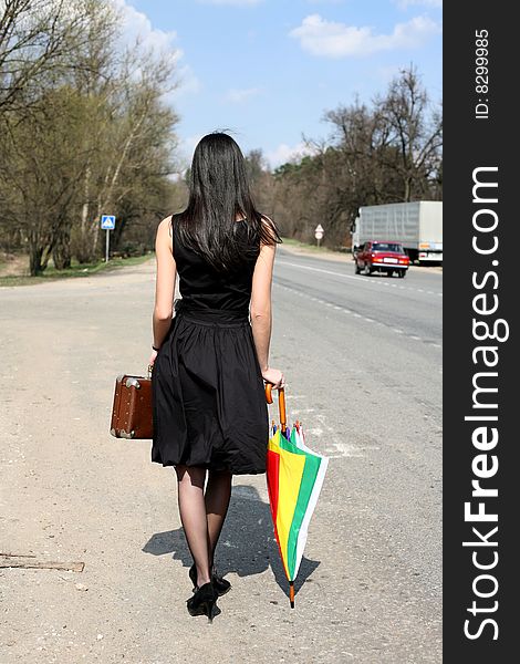 Girl with vintage suitcase and umbrella outdoors