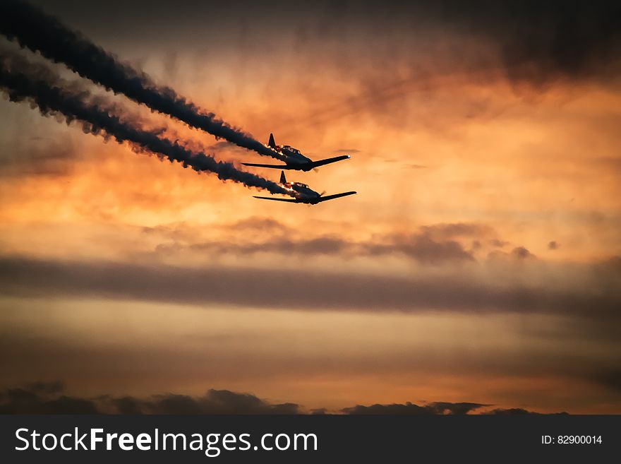 Airplanes flying in formation against setting sun with black smoke trails. Airplanes flying in formation against setting sun with black smoke trails.