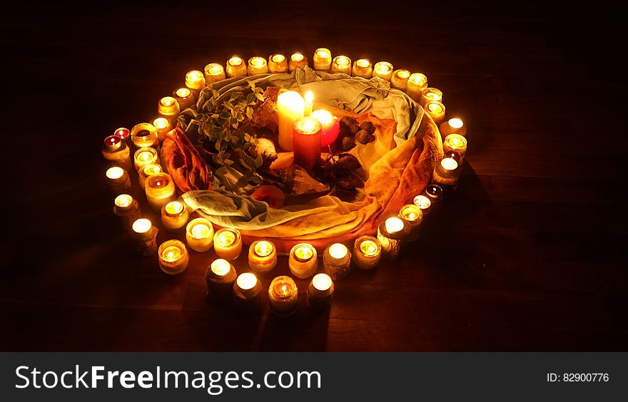 Ring of illuminated candles in display with colorful cloth on black. Ring of illuminated candles in display with colorful cloth on black.