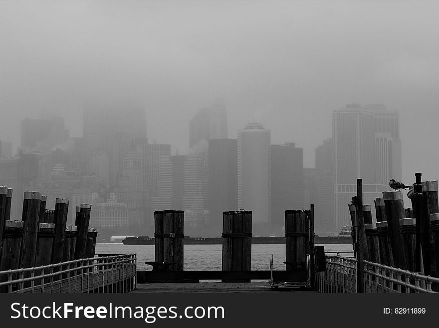 Wharf along waterfront with Manhattan, New York skyline in fog.