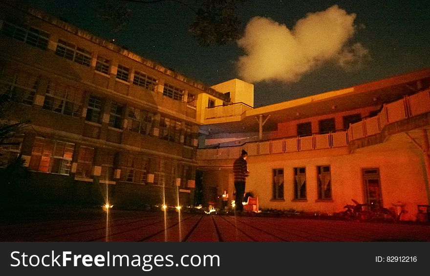 Outside courtyard illuminated with lamps at night with smoke or steam coming from building. Outside courtyard illuminated with lamps at night with smoke or steam coming from building.