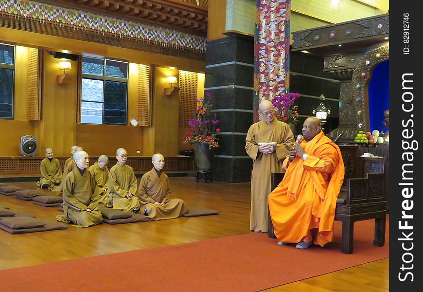 Monks in robes seated inside modern temple. Monks in robes seated inside modern temple.