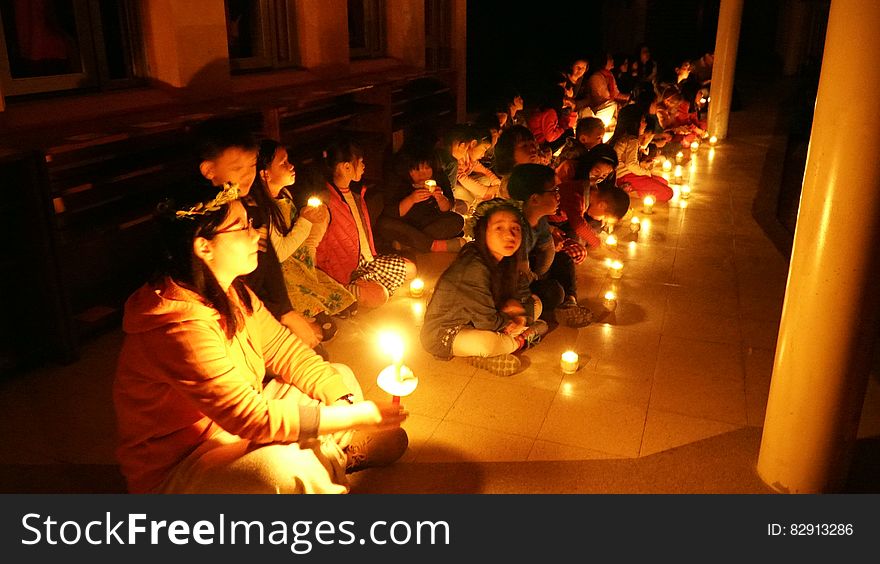 Children sitting with candles inside room. Children sitting with candles inside room.