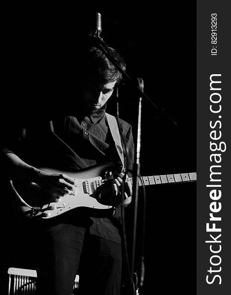 Musician onstage playing electric guitar in black and white. Musician onstage playing electric guitar in black and white.