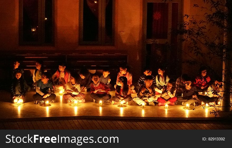 Children seated on floor indoors with candles during candlelight ceremony. Children seated on floor indoors with candles during candlelight ceremony.