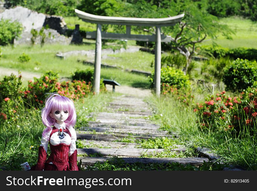 Doll along path through garden with gazebo on sunny day. Doll along path through garden with gazebo on sunny day.