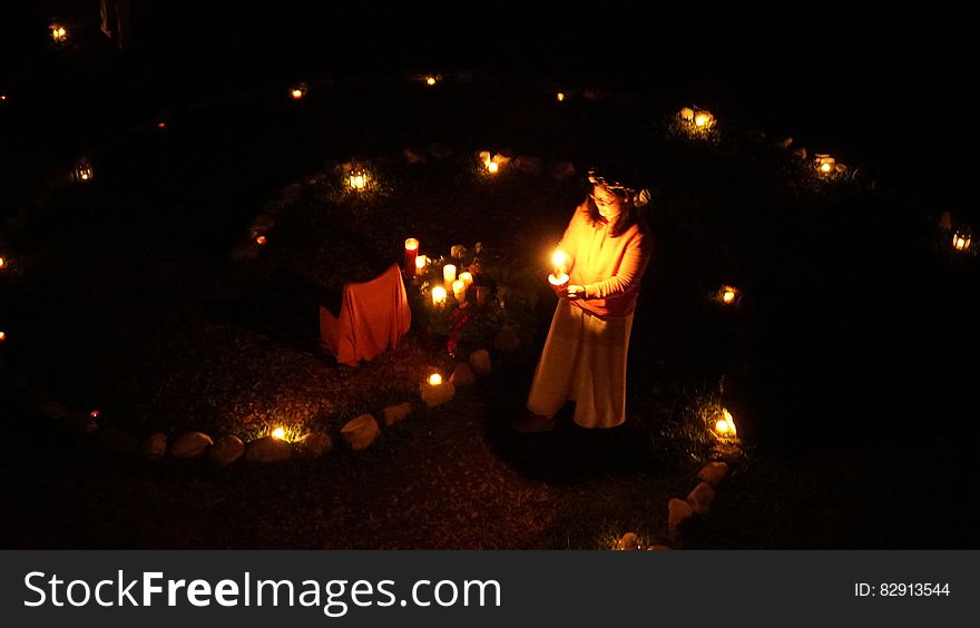 Girl holding candles outdoors in garden illuminated with lanterns. Girl holding candles outdoors in garden illuminated with lanterns.