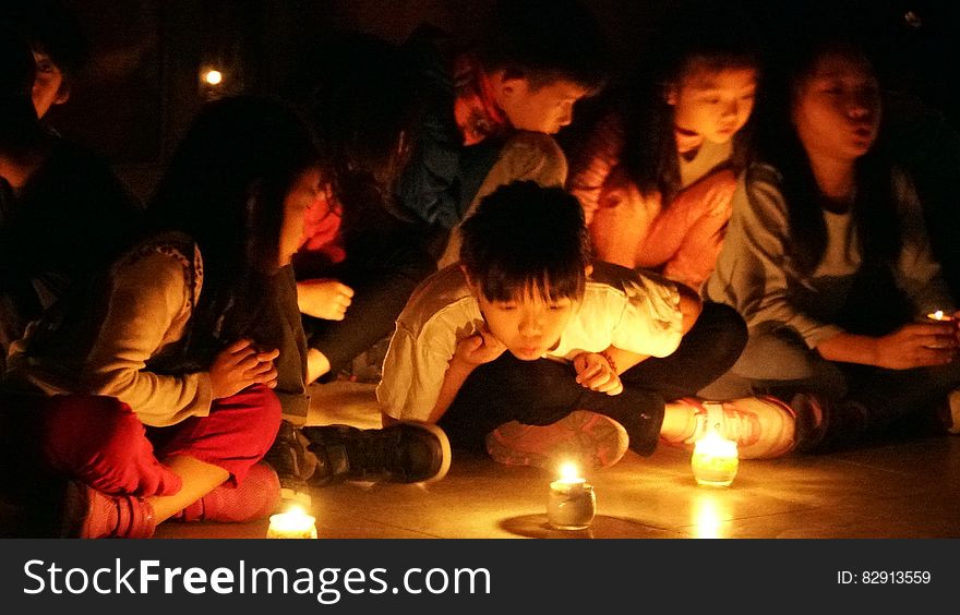 Children sitting on floor looking at candles burning. Children sitting on floor looking at candles burning.