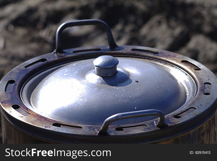 Close up of metal pot with lid outdoors on sunny day.