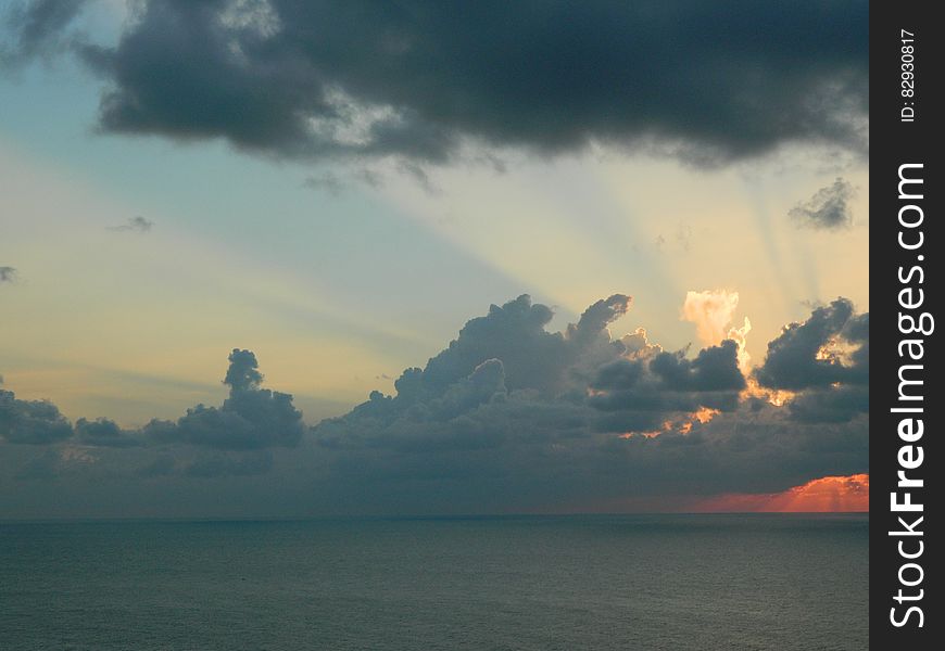 Clouds in skies over water with setting sun and blue skies. Clouds in skies over water with setting sun and blue skies.