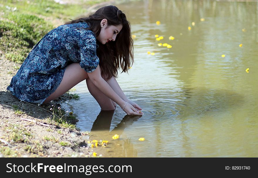 Woman Soaking Her Feet on Body of Water during Daytime