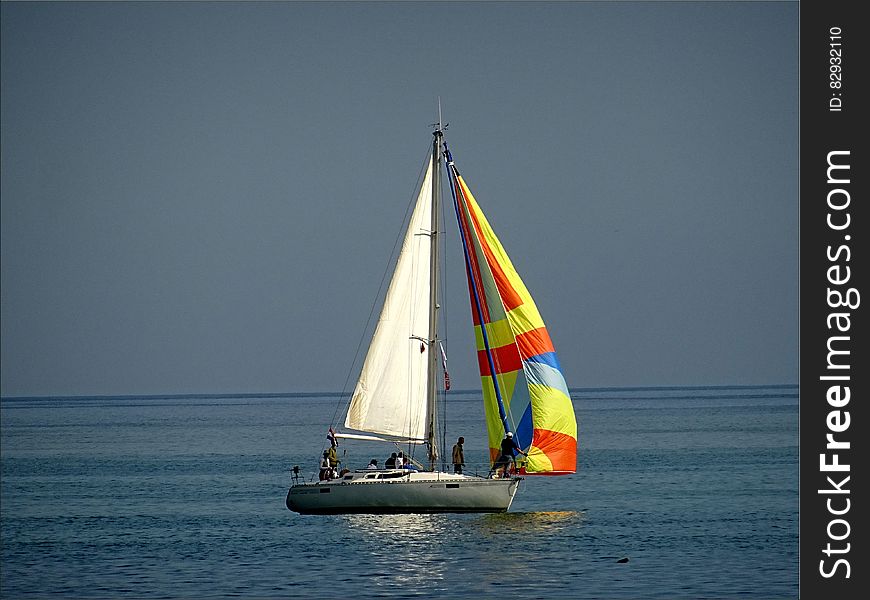 Gray And White Sail Boat With 5 Person Riding On The Middle Of The Body Of Water