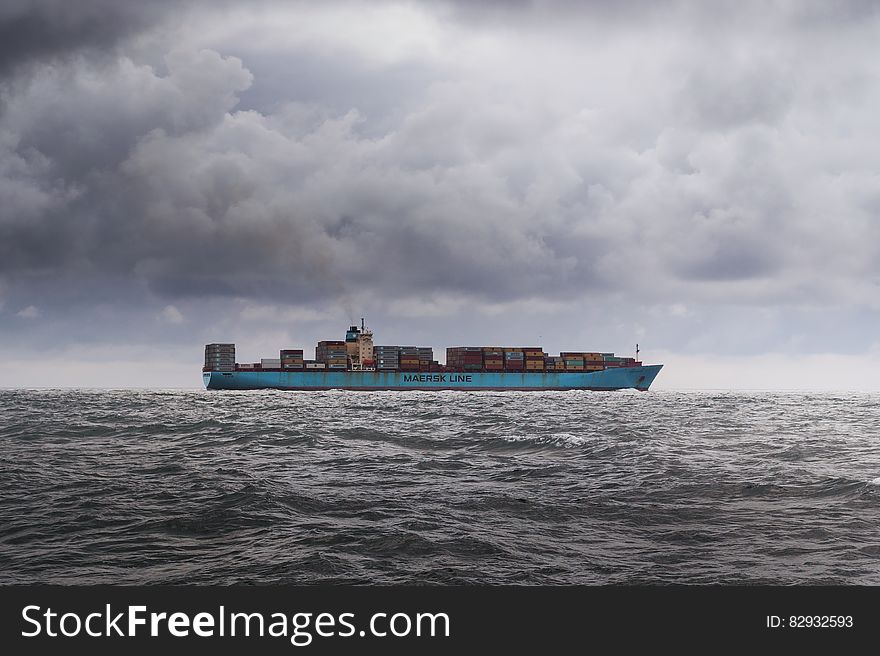 Cargo ship navigating grey choppy waters with stormy skies. Cargo ship navigating grey choppy waters with stormy skies.