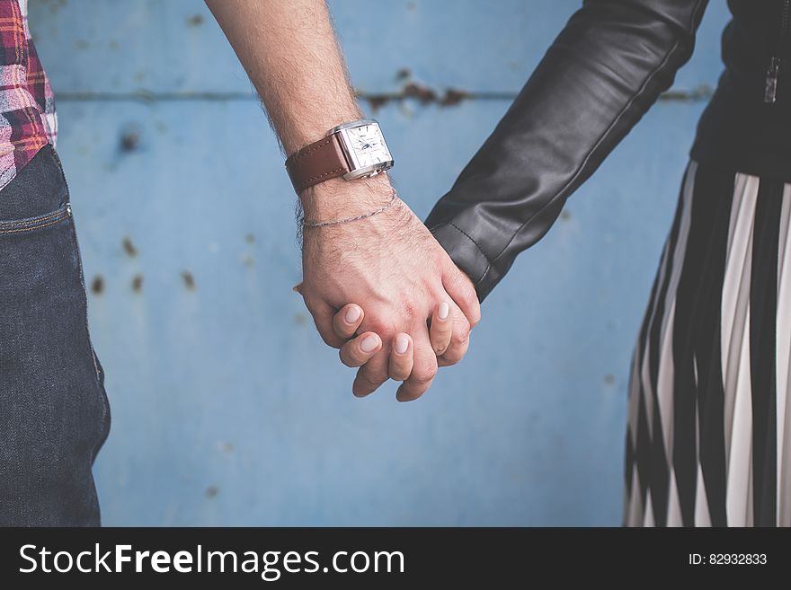 2 Person Holding Hands Besides Blue Painted Wall