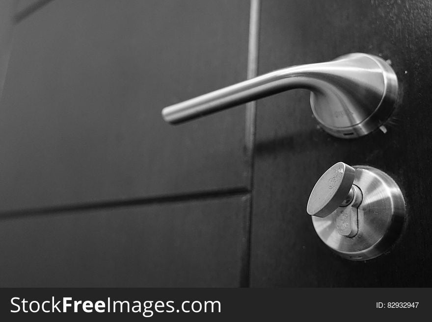 Close up of metal door knob and dead bolt lock on door in black and white. Close up of metal door knob and dead bolt lock on door in black and white.