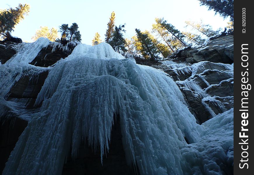 Frozen icicles on waterfalls over steep rocks on sunny day. Frozen icicles on waterfalls over steep rocks on sunny day.